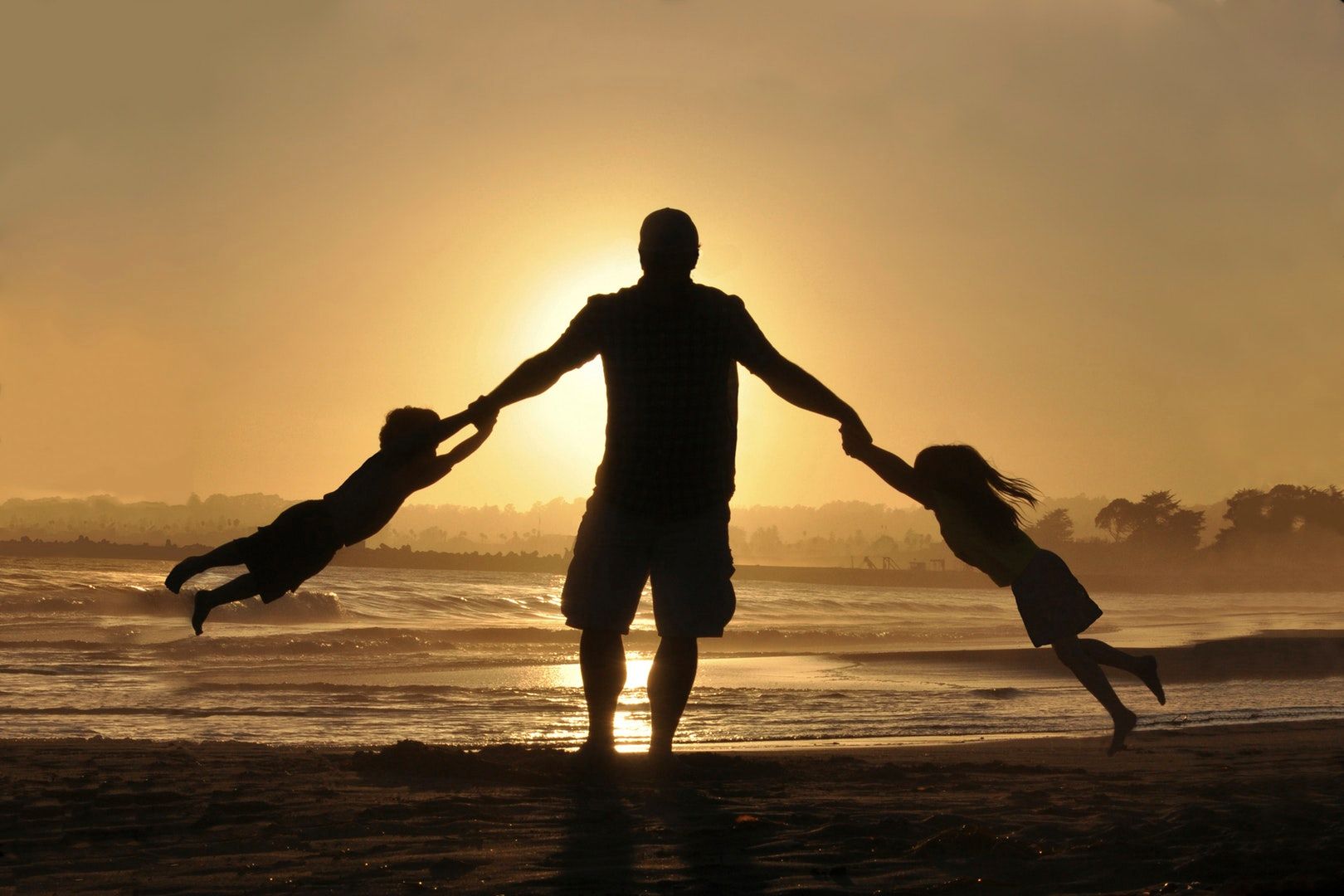 Dad and kids playing on the beach at sunset