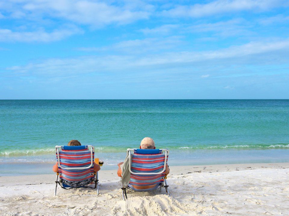 Retired couple sitting in beach chairs enjoying the ocean